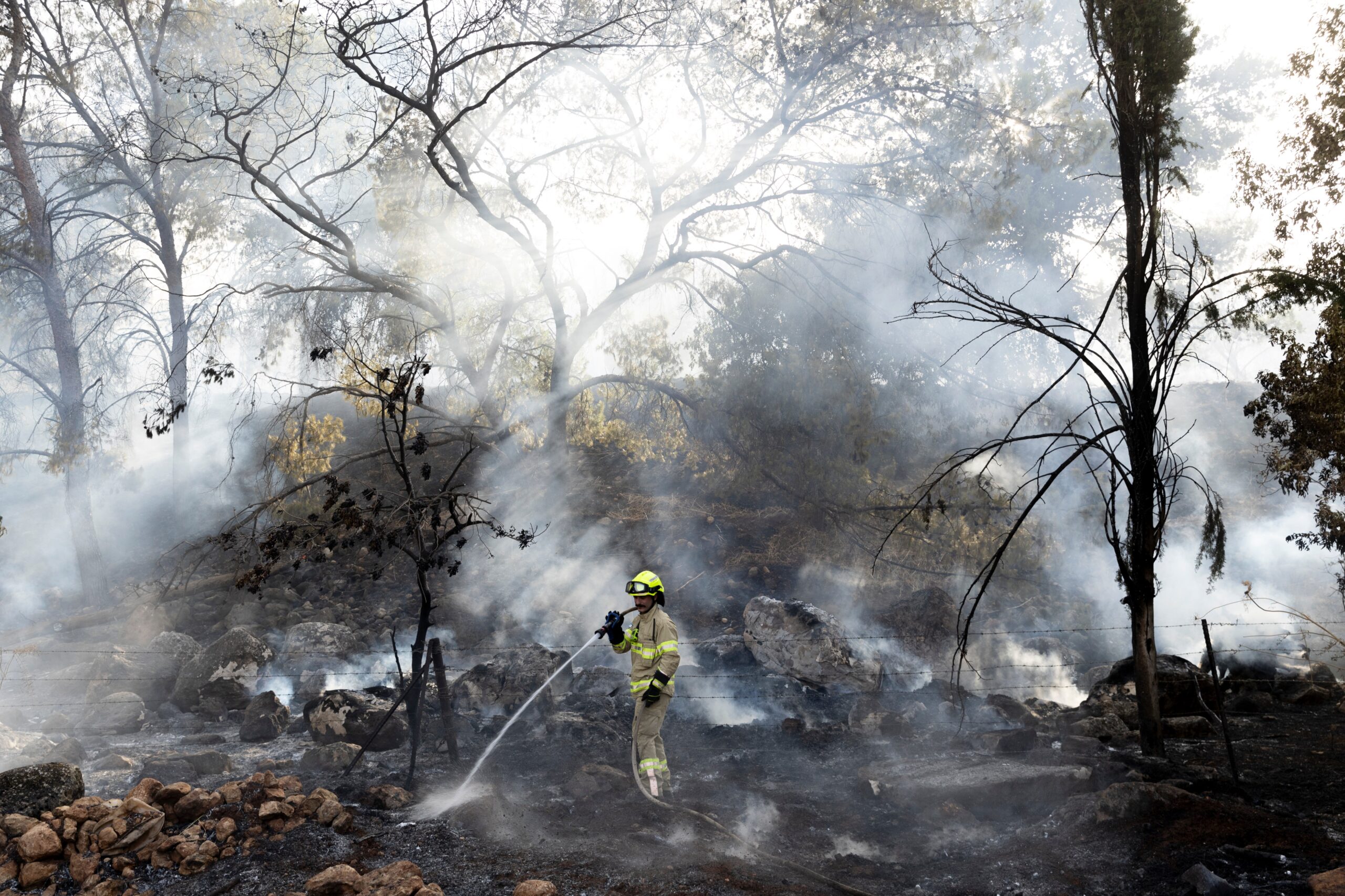 An Israeli firefighter douses a fire that broke out after a rocket strike fired from Lebanon on July 4 in northern Israel